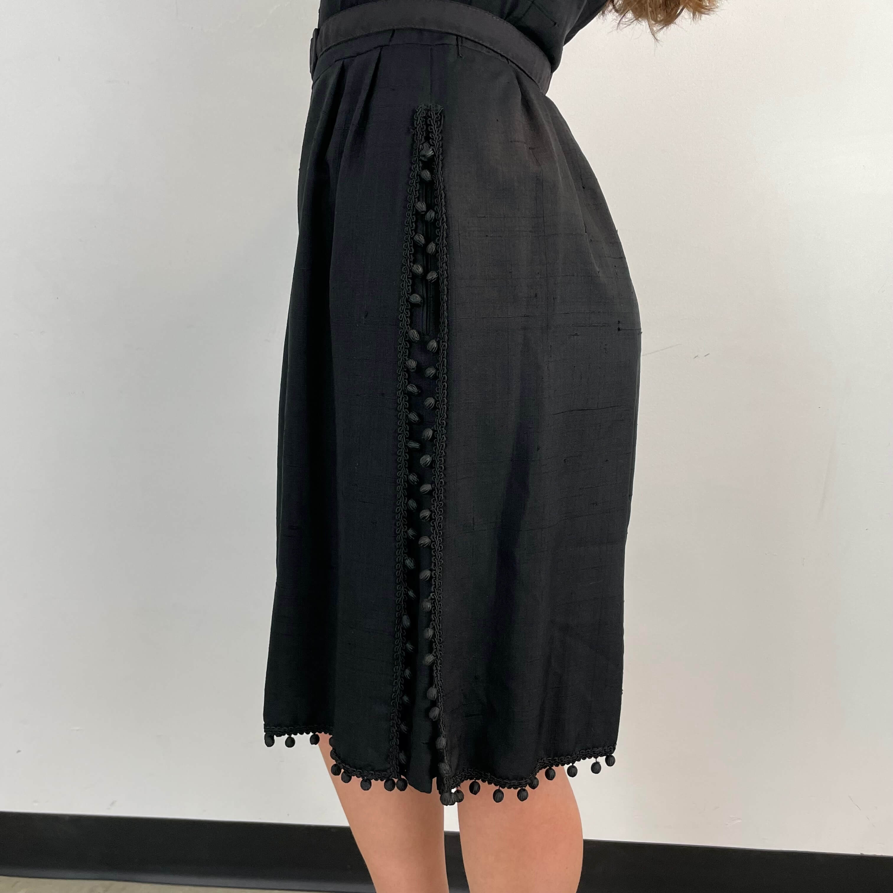 Close-up view of side and hem detailing of 1950s Black Short-Sleeve Cocktail Dress size medium sold at bohemevintage.com Montreal