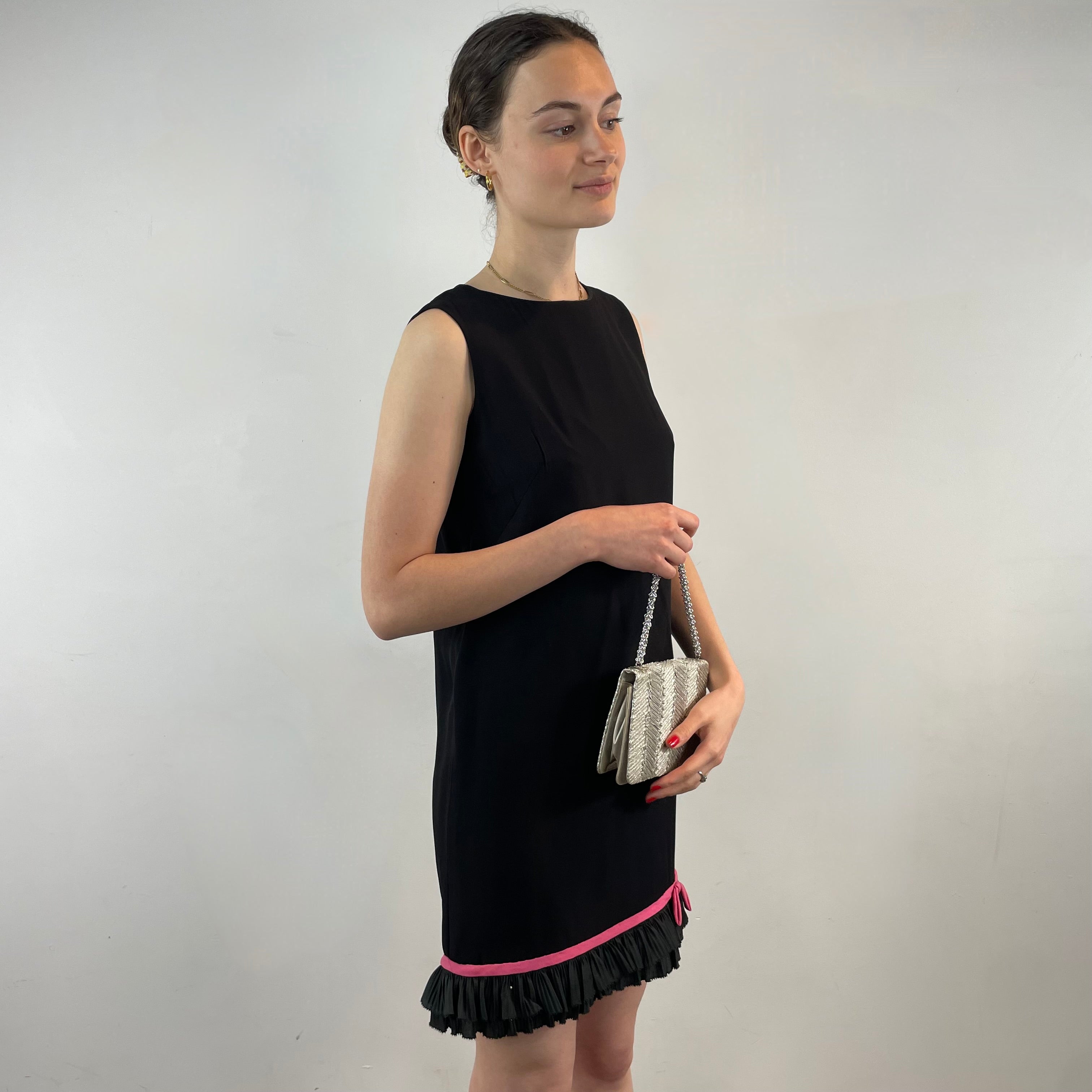 Boheme Vintage 1960s black crepe shift dress with pink ribbon bow hem, sleeveless silhouette, and crew neckline.
