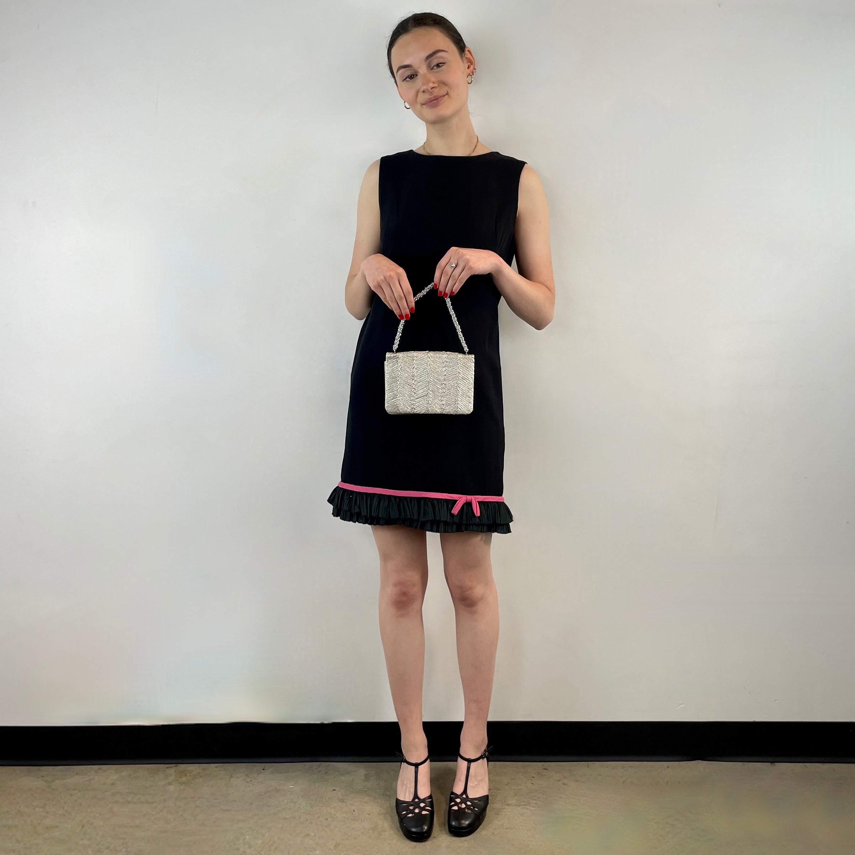 Boheme Vintage 1960s black crepe shift dress with pink ribbon bow hem, sleeveless silhouette, and crew neckline.