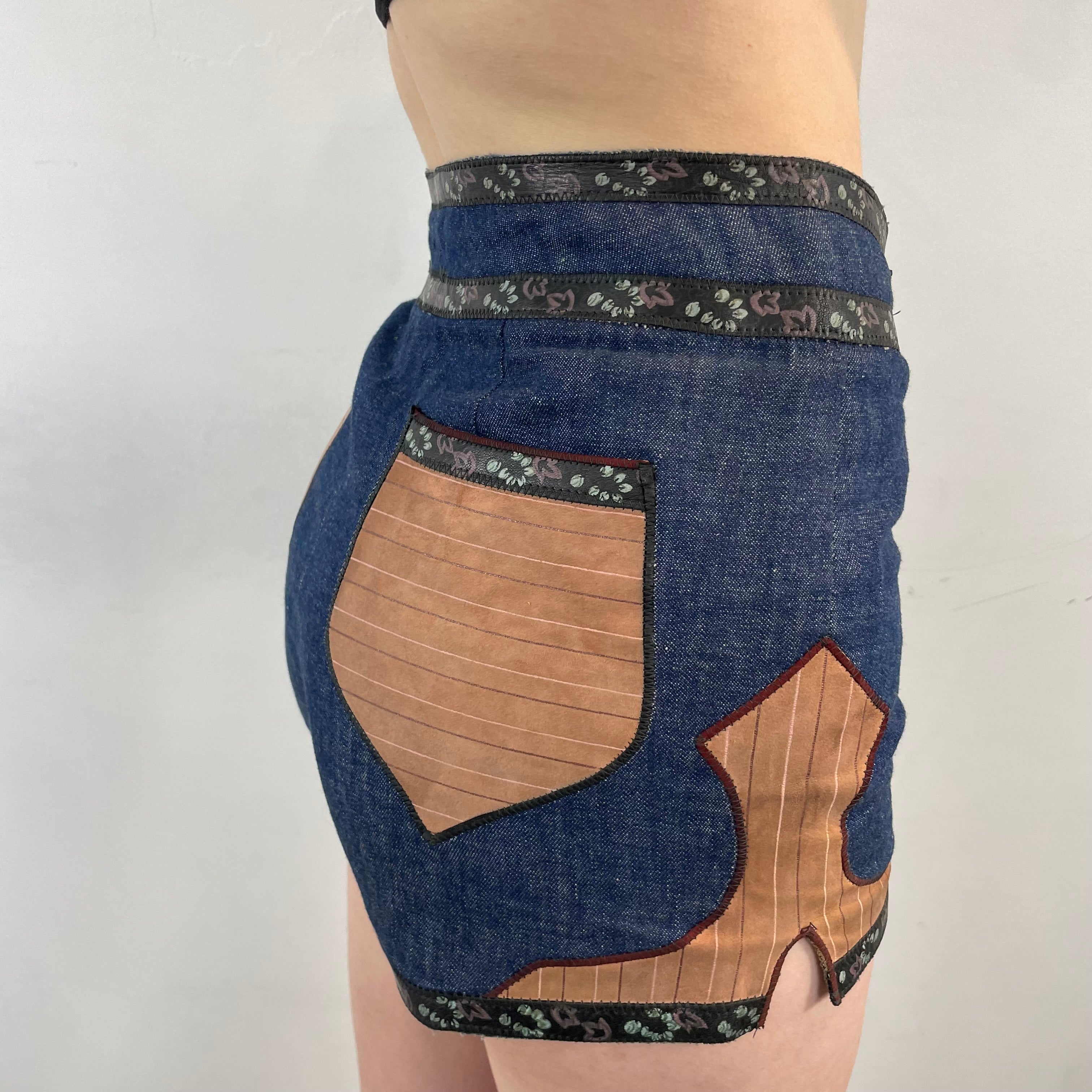 Boheme Vintage 1970s Roberto Cavalli denim and leather hot pants shorts with flower snap closures and leather appliqué details.