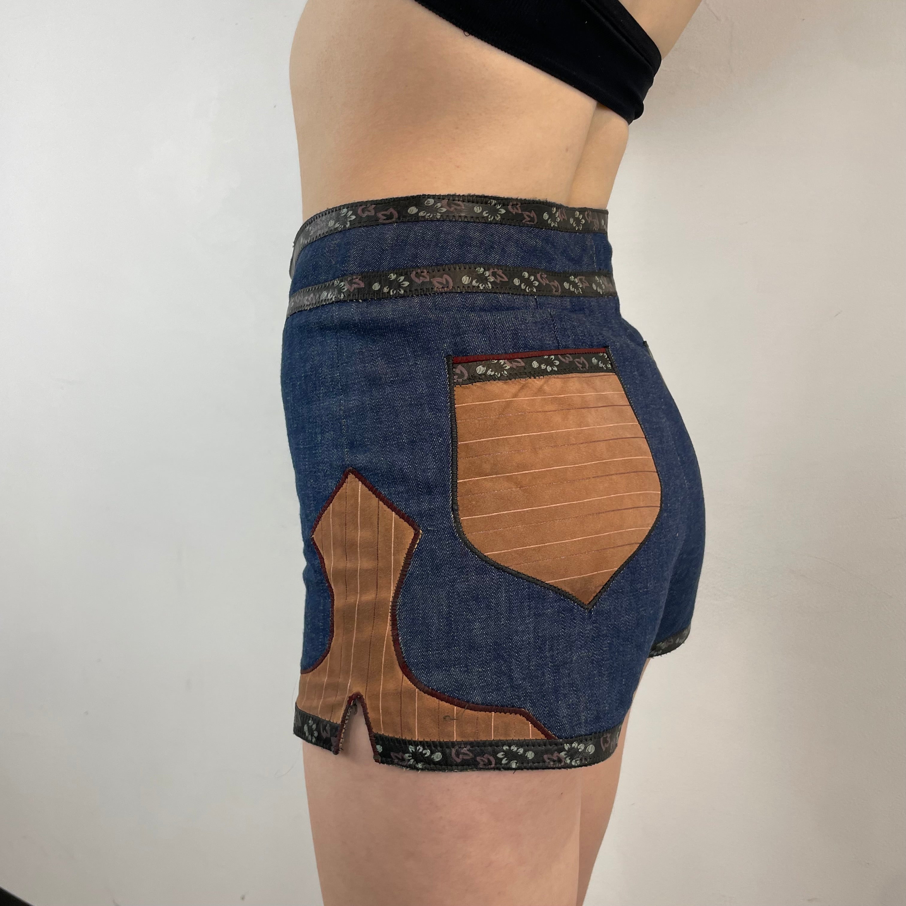 Boheme Vintage 1970s Roberto Cavalli denim and leather hot pants shorts with flower snap closures and leather appliqué details.