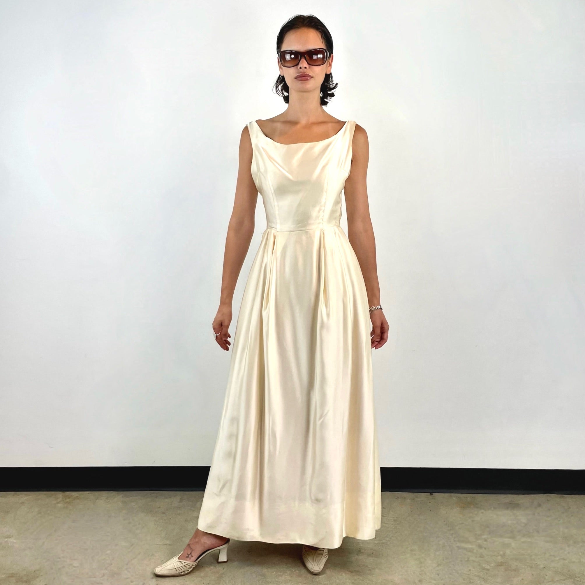 Boheme Vintage 1970s ivory satin gown with open back, pleated skirt, and fitted bodice.