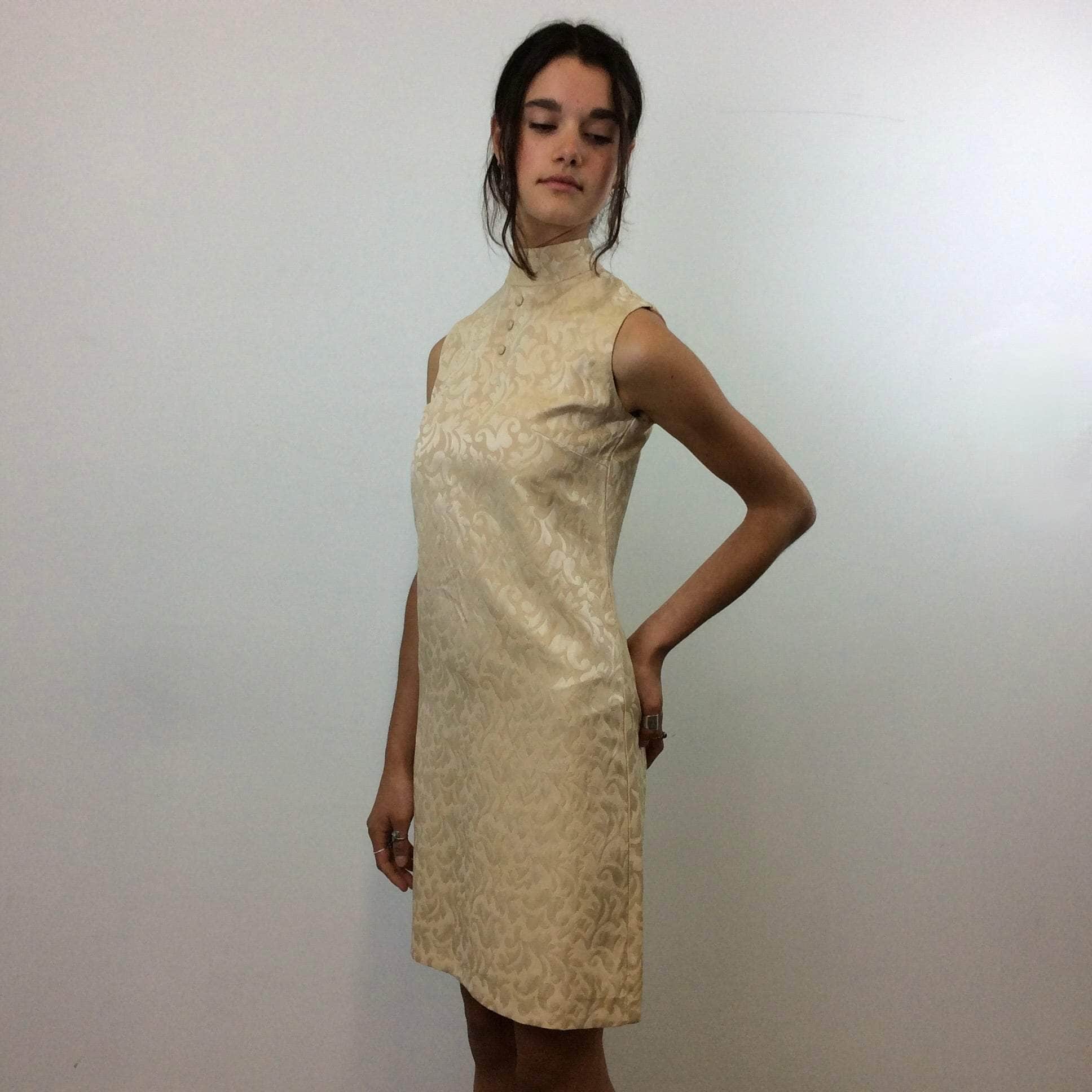 Side view of 1960s Beige Brocade Sleeveless Satin Shift Dress Small. Sold by Bohème Vintage. Montreal.