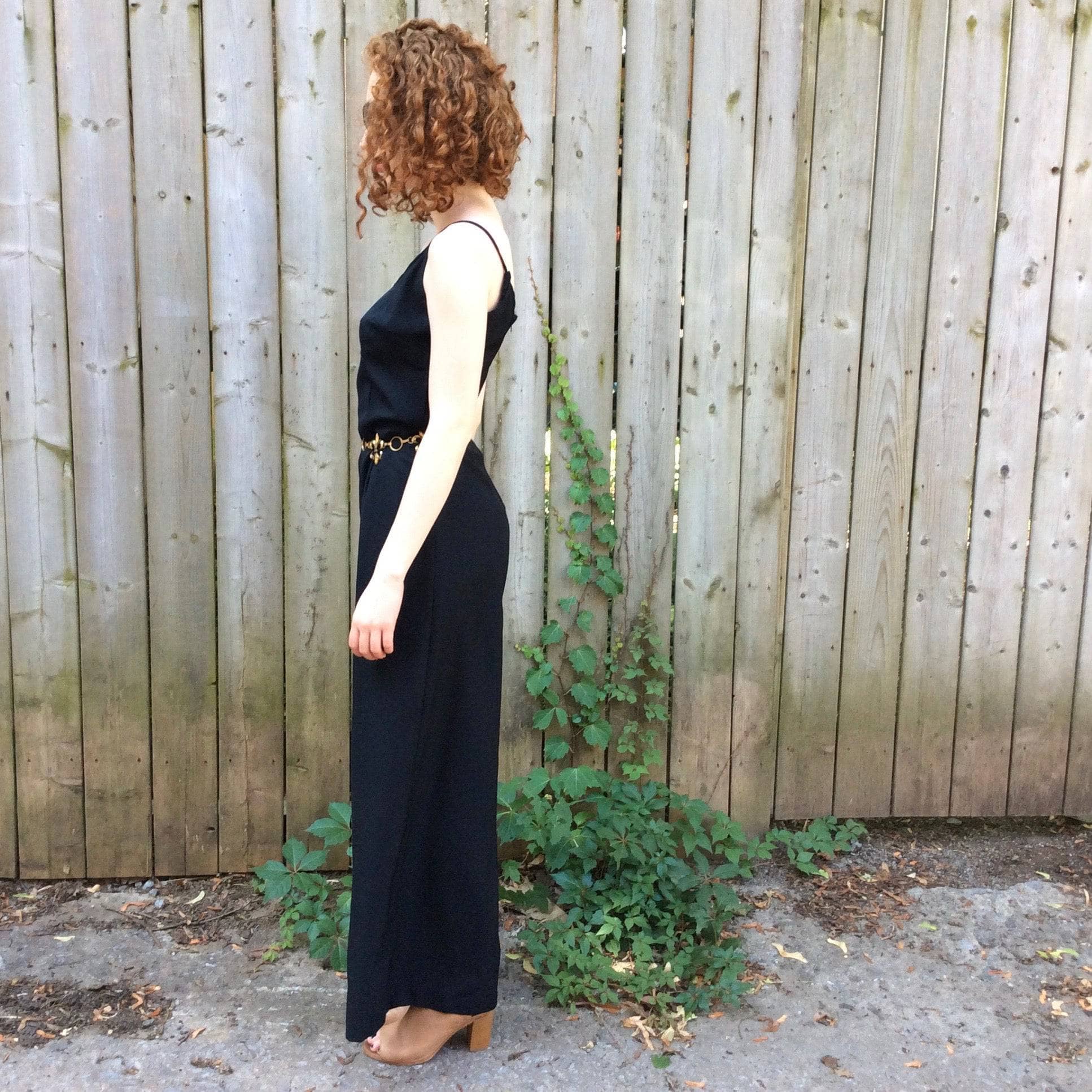 Side View of Boheme Vintage 1980s black wide-leg jumpsuit with fitted bodice, adjustable straps, and flowing silhouette.