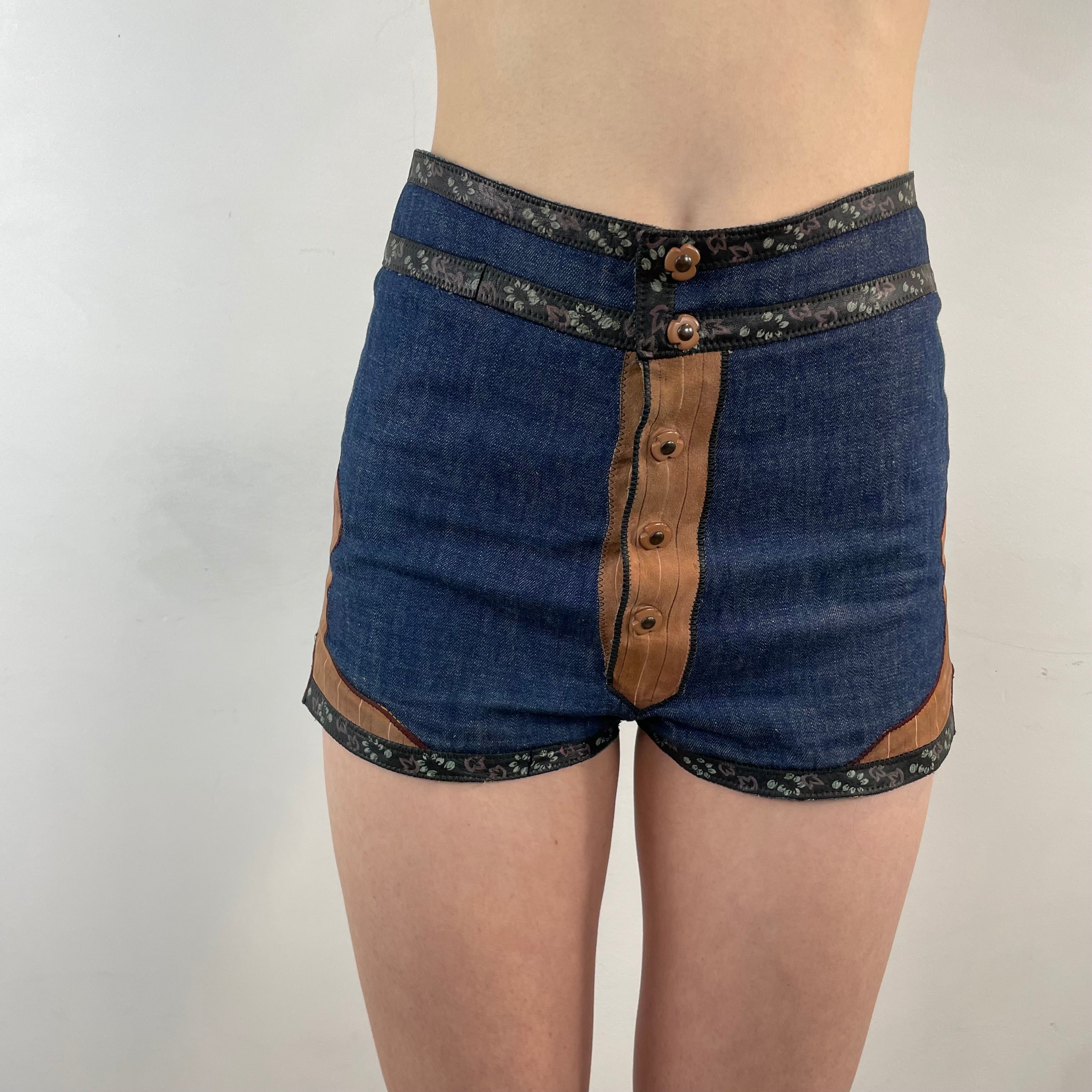 Boheme Vintage 1970s Roberto Cavalli denim and leather hot pants shorts with flower snap closures and leather appliqué details.