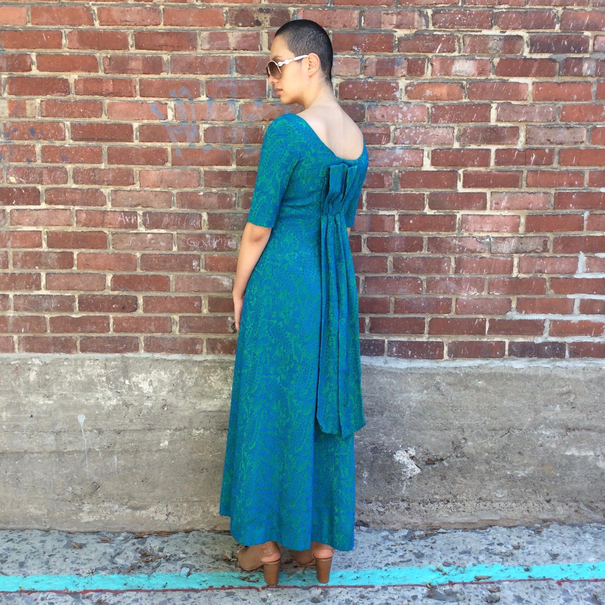 Decorative detailing of the back of Vintage 1960s blue and green brocade ankle-length evening dress with empire waist and low back detail, photographed in Montreal for Boheme Vintage – https://bohemevintage.com
 – Montreal vintage fashion boutique.